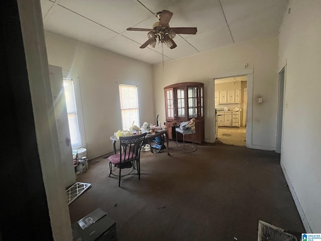 unfurnished dining area featuring a ceiling fan and dark colored carpet