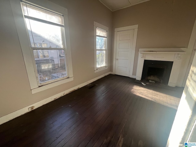 unfurnished living room with dark wood-type flooring, baseboards, and a fireplace with flush hearth