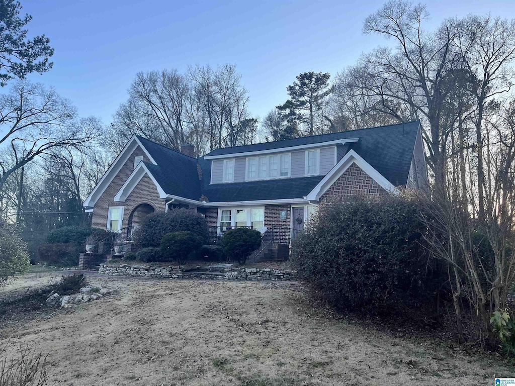 traditional-style house with a chimney and brick siding