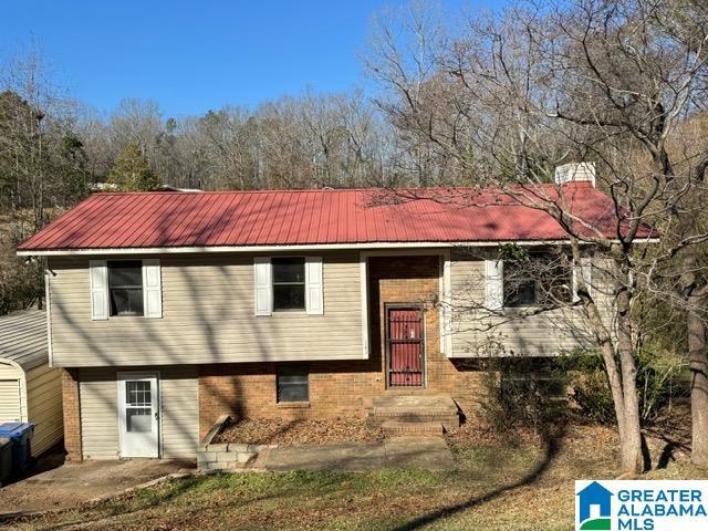 raised ranch featuring metal roof and brick siding