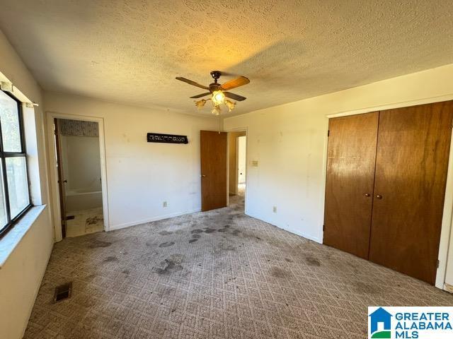 unfurnished bedroom with a textured ceiling, a closet, visible vents, and carpet flooring