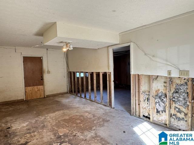 unfurnished room featuring a textured ceiling and unfinished concrete flooring