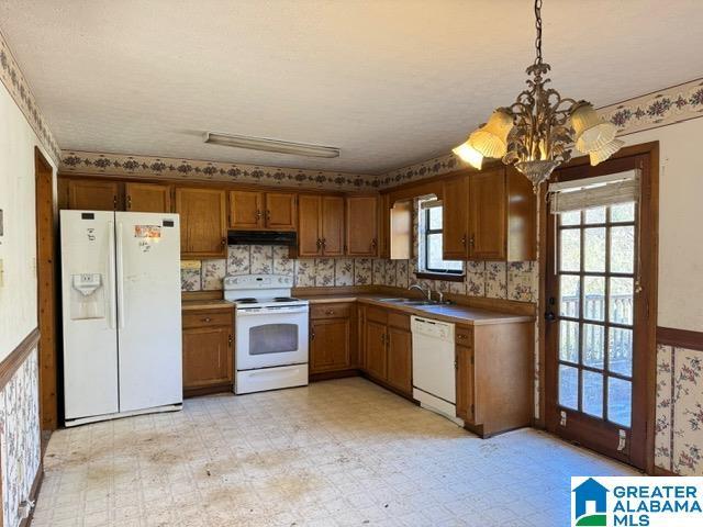 kitchen featuring white appliances, light floors, light countertops, under cabinet range hood, and pendant lighting