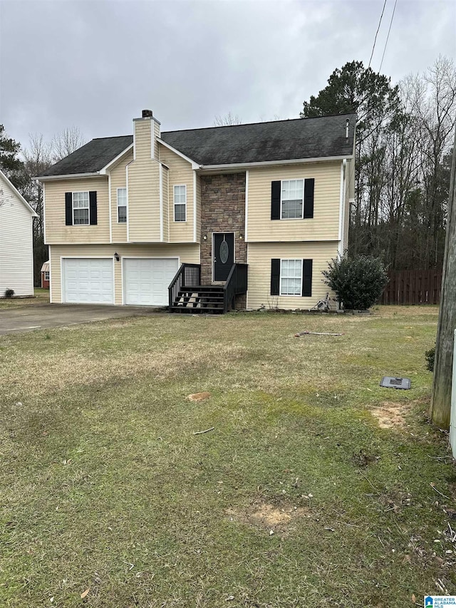 raised ranch with driveway, stone siding, an attached garage, and a front lawn