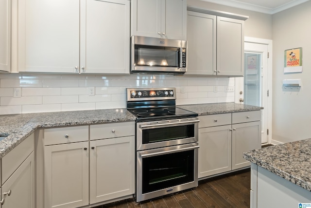 kitchen with appliances with stainless steel finishes, light stone countertops, dark wood-style floors, and tasteful backsplash