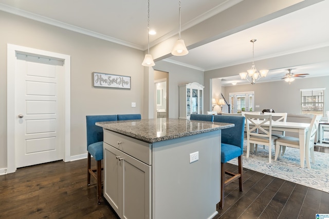 kitchen featuring dark wood-type flooring, open floor plan, ornamental molding, and a breakfast bar area