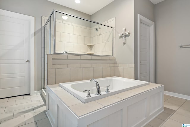 bathroom with a stall shower, tile patterned flooring, a garden tub, and baseboards