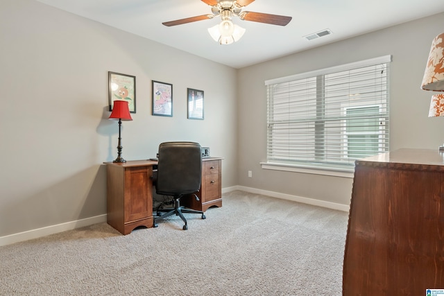 home office featuring light carpet, a ceiling fan, visible vents, and baseboards