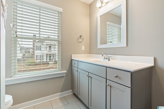 half bathroom featuring toilet, plenty of natural light, tile patterned flooring, and vanity