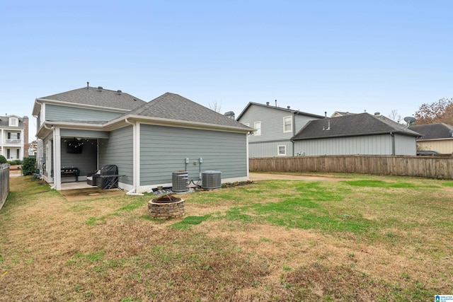 back of property featuring roof with shingles, central air condition unit, a lawn, an outdoor fire pit, and fence