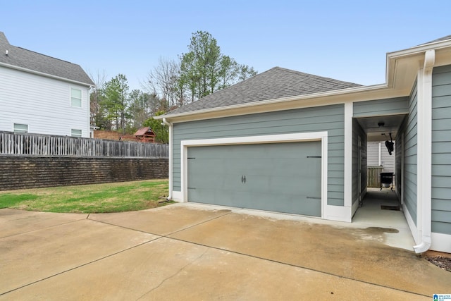 garage with concrete driveway and fence