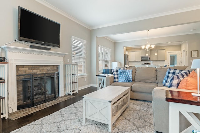 living room featuring a chandelier, wood finished floors, baseboards, ornamental molding, and a brick fireplace