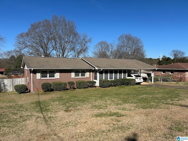 single story home with a carport, a front yard, brick siding, and fence