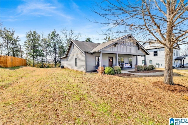 view of front of house featuring board and batten siding, a front yard, central AC, and fence