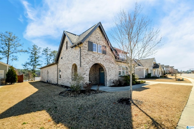 view of front facade with brick siding and a front lawn