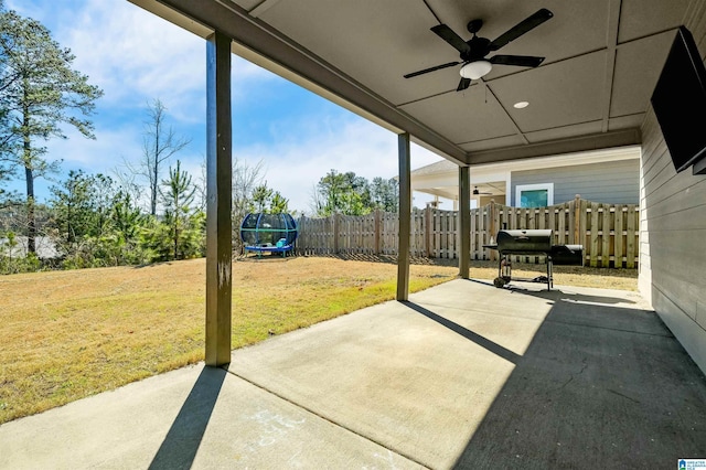 view of patio featuring a trampoline, fence, grilling area, and ceiling fan