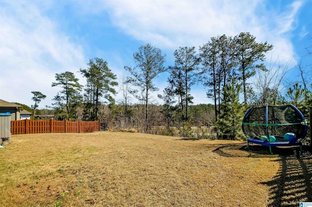 view of yard with a trampoline and fence