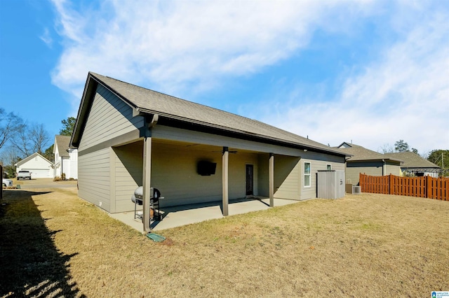 rear view of house with ceiling fan, a lawn, a patio area, and fence