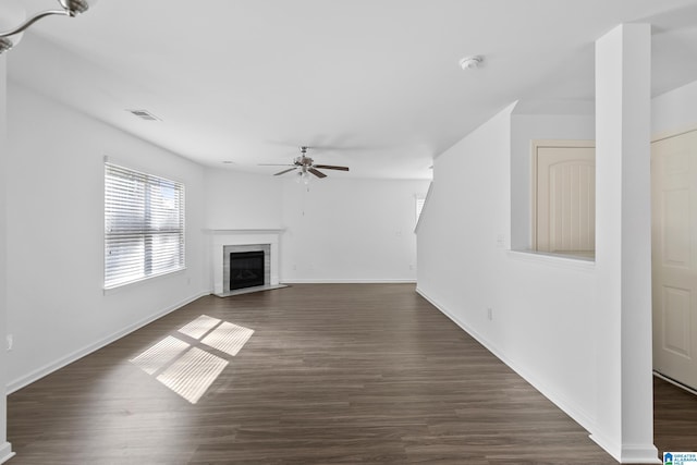 unfurnished living room featuring visible vents, dark wood finished floors, baseboards, ceiling fan, and a fireplace