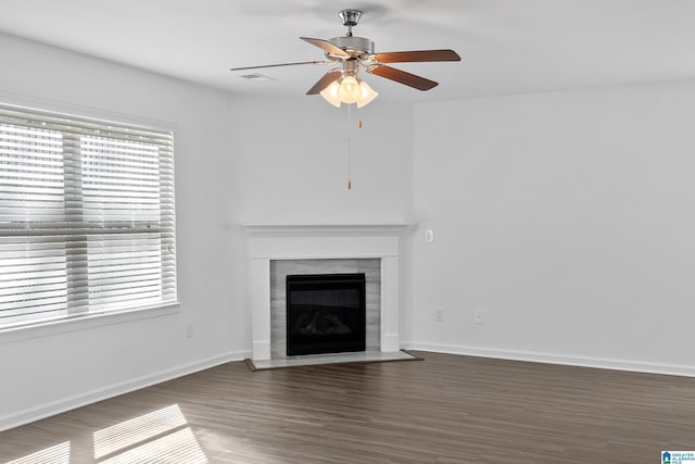 unfurnished living room with ceiling fan, a fireplace with flush hearth, dark wood finished floors, and baseboards