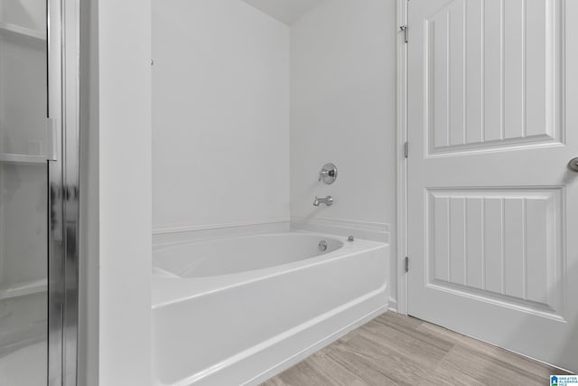 full bath featuring wood finished floors and a bath