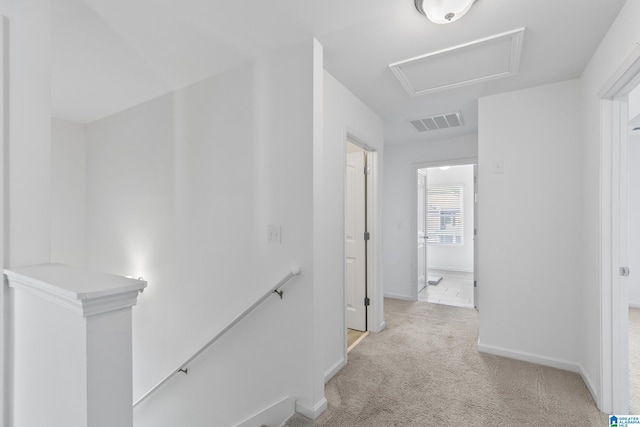 hall featuring light carpet, visible vents, baseboards, an upstairs landing, and attic access