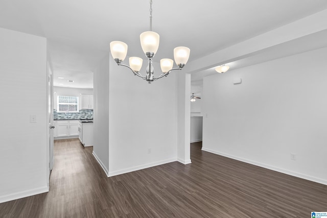 unfurnished dining area featuring ceiling fan with notable chandelier, dark wood-type flooring, and baseboards