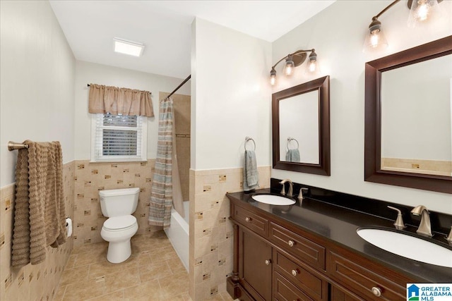 bathroom featuring shower / tub combo, a wainscoted wall, a sink, and tile walls