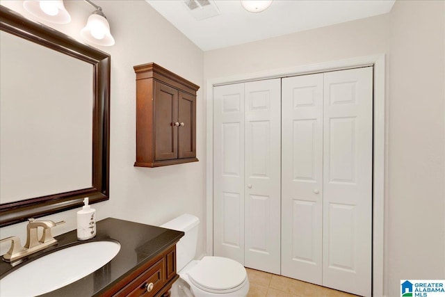 half bath featuring a closet, visible vents, toilet, vanity, and tile patterned flooring