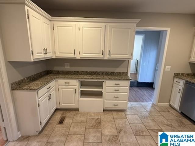 kitchen with dark stone counters, stainless steel dishwasher, baseboards, and white cabinets