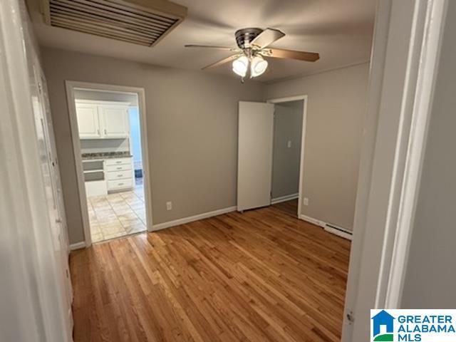 empty room featuring baseboards, light wood-style flooring, visible vents, and a ceiling fan