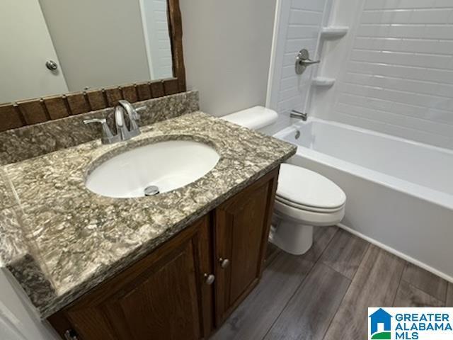 full bath featuring vanity, shower / bathing tub combination, wood finished floors, and toilet