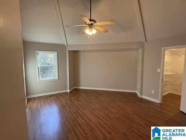 interior space with ceiling fan, dark wood-type flooring, vaulted ceiling, and baseboards