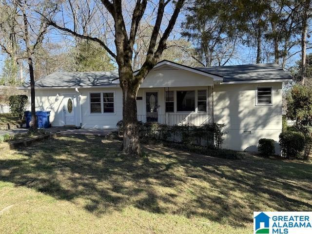 ranch-style house featuring covered porch and a front yard