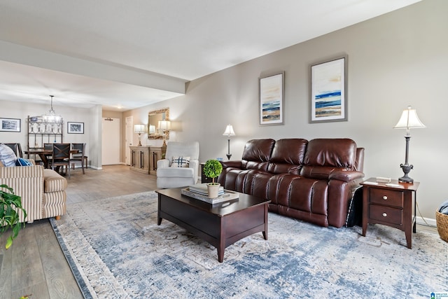 living room featuring an inviting chandelier, light wood-style flooring, and baseboards