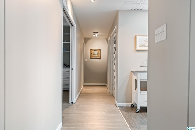 corridor with light wood-style flooring and baseboards