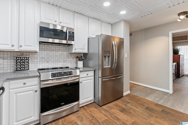 kitchen with white cabinetry, appliances with stainless steel finishes, tasteful backsplash, and baseboards