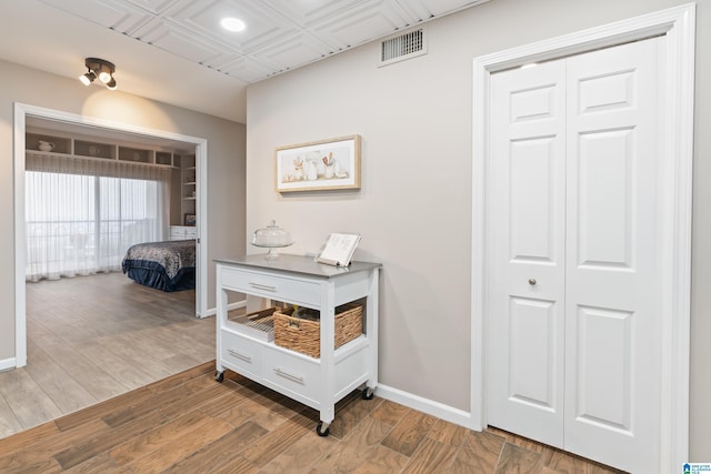 hallway with baseboards, visible vents, and wood finished floors