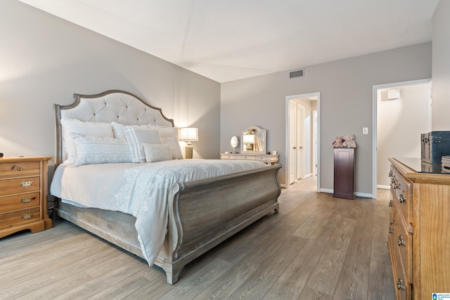 bedroom with visible vents, baseboards, and wood finished floors