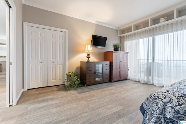 bedroom featuring ornamental molding, a closet, light wood-style floors, and baseboards