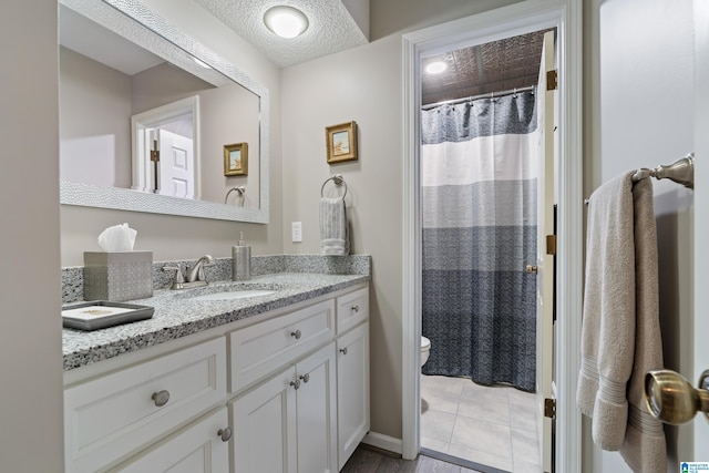 bathroom with baseboards, toilet, a shower with curtain, a textured ceiling, and vanity