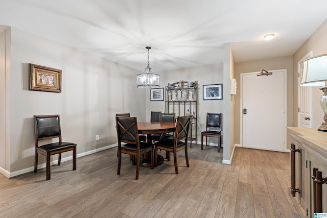 dining area with light wood-style floors, baseboards, and a chandelier