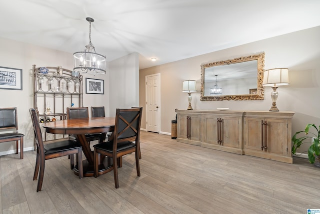 dining space with an inviting chandelier, light wood-style flooring, and baseboards