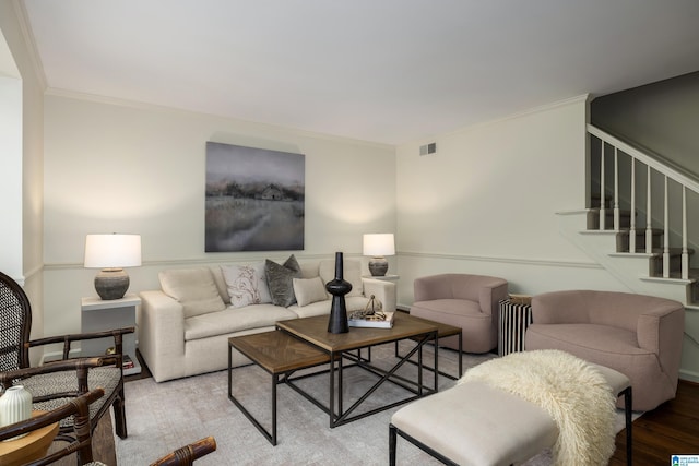 living room featuring visible vents, stairway, light wood-style flooring, and ornamental molding