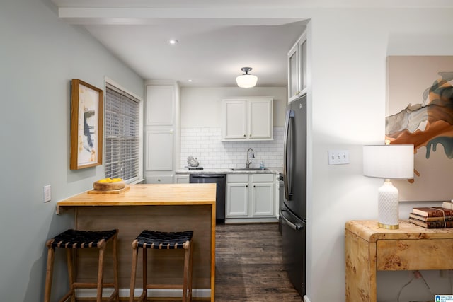 kitchen with black dishwasher, white cabinets, decorative backsplash, freestanding refrigerator, and a sink