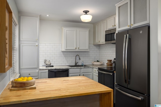 kitchen with stainless steel appliances, decorative backsplash, a sink, and white cabinets