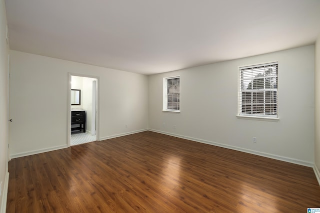 spare room featuring dark wood-type flooring and baseboards