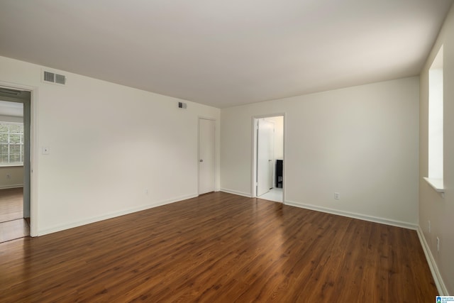 spare room featuring dark wood-style floors, visible vents, and baseboards