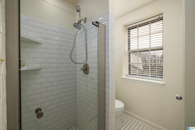 bathroom with toilet, a shower stall, and baseboards