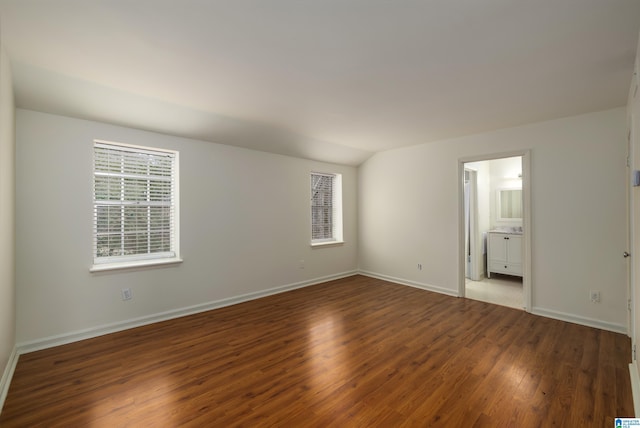 unfurnished room featuring vaulted ceiling, dark wood-style flooring, and baseboards